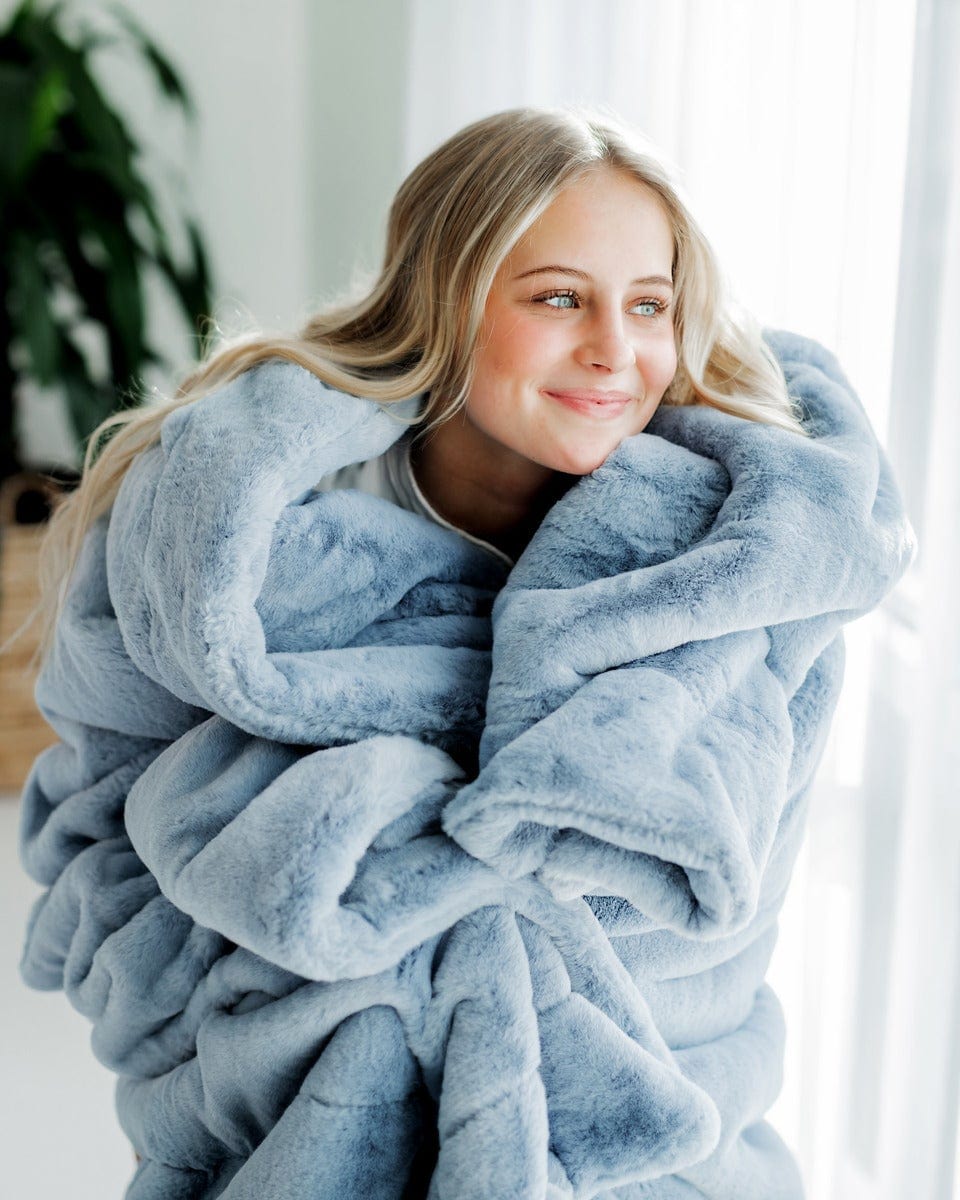 Young woman wrapped up in a denim blue thick plush blanket.