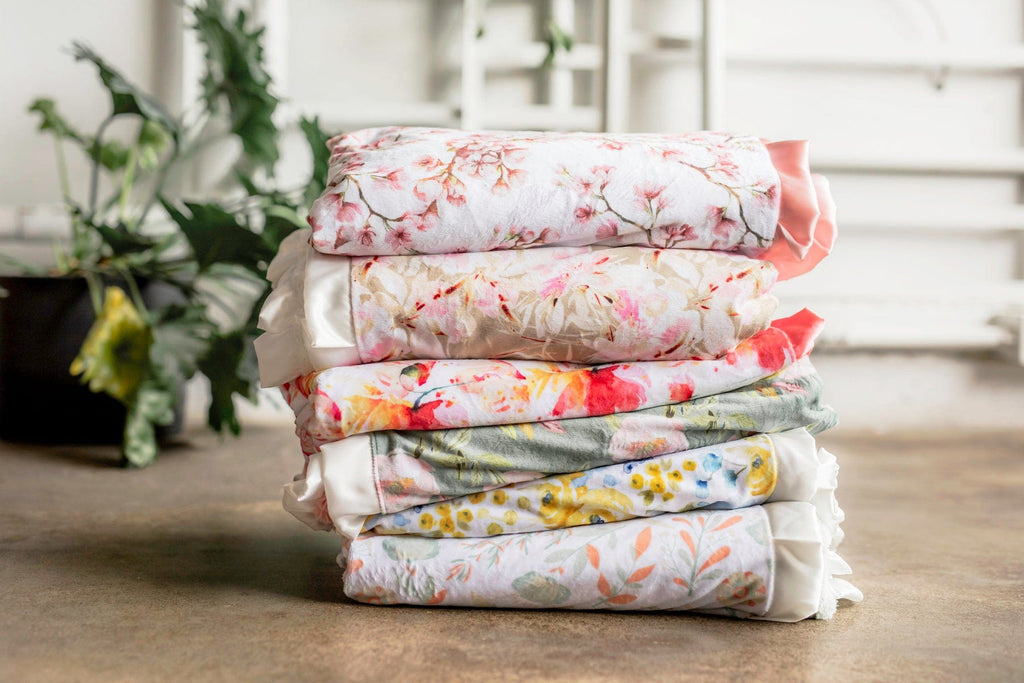 Stack of six different floral Minky Couture blankets. 