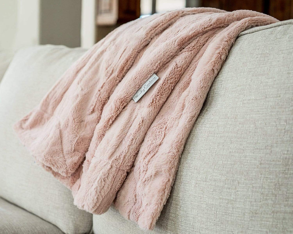 Sorbet Blush Pink minky blanket laid over a cream couch.